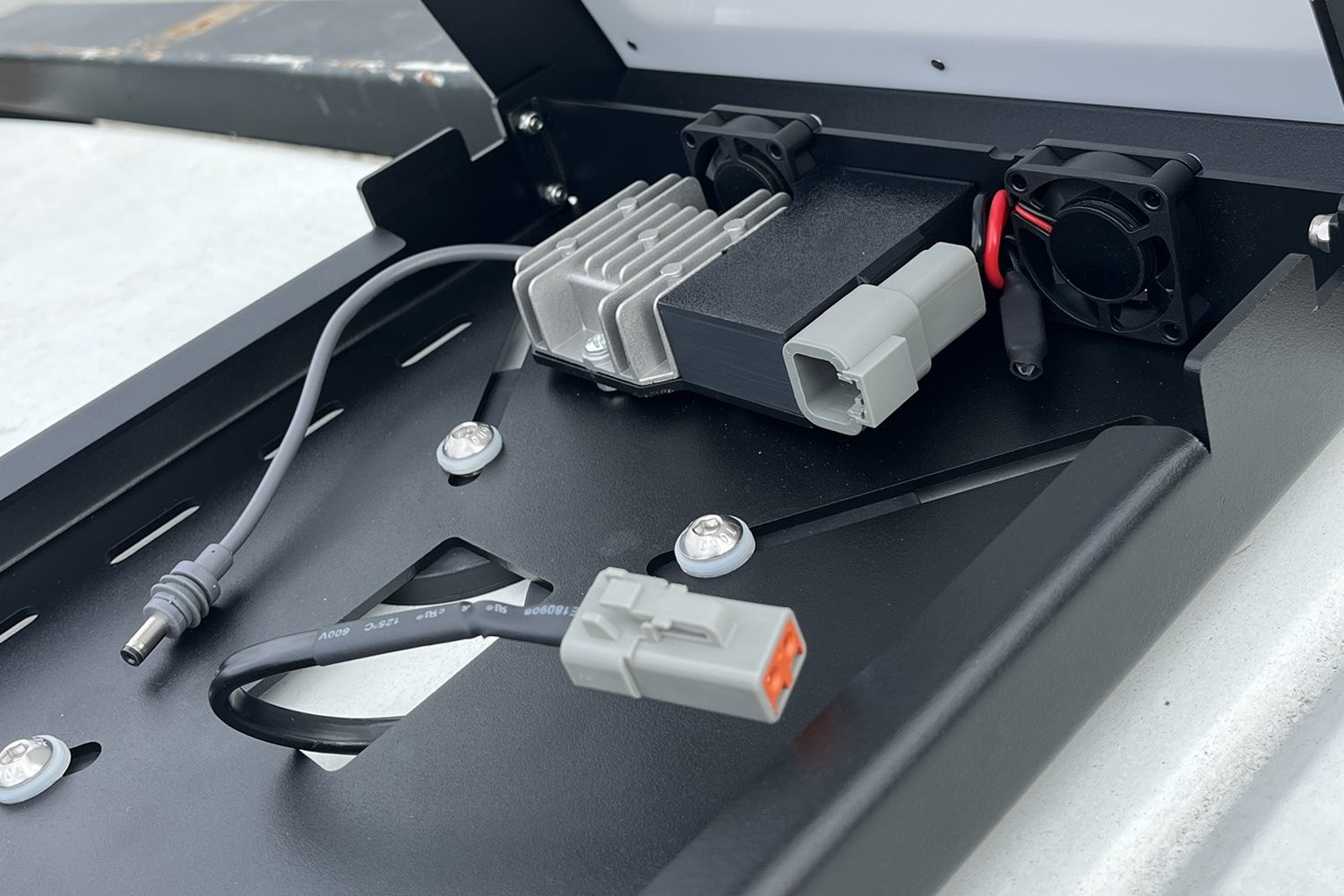 Inside the opened Fan-Cooled Rooftop Power Hub, showing 30v step-up converter, sealed deutsch-style plug — 12v input, dual ip67 cooling fans, automotive thermostat switch, harness plug from the vehicle, oem sealed output plug.
