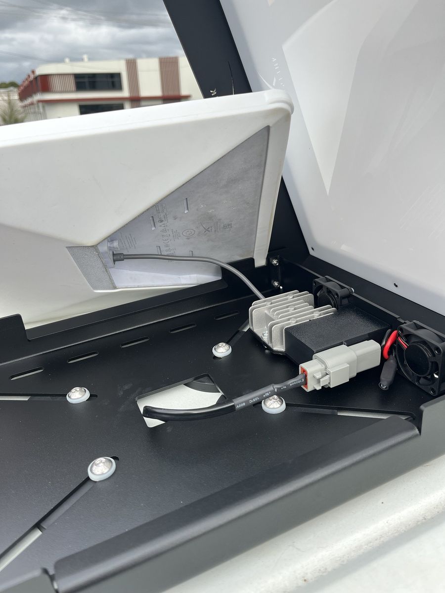 The Power Hub's grey lead plugged into the back of the Starlink Mini as it is lowered into the mount